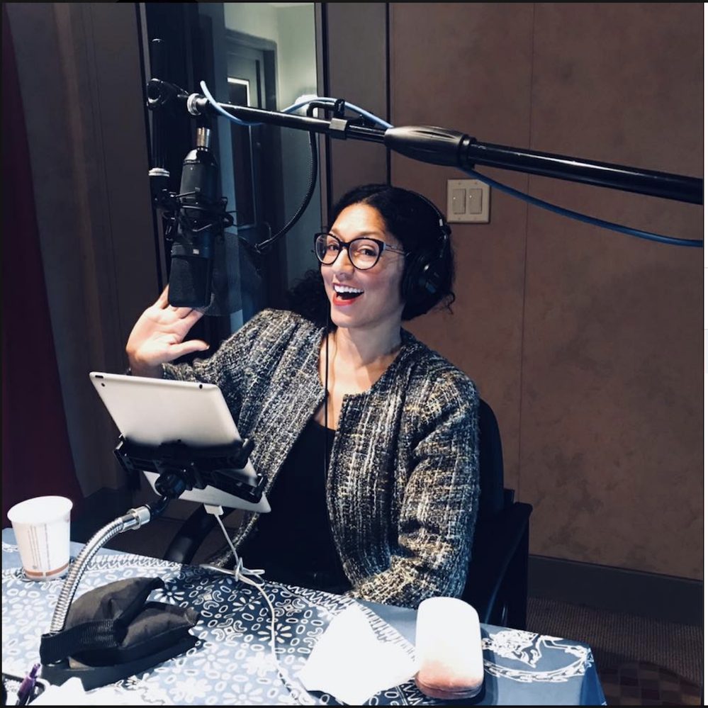 Maya Contreras in glasses sits at a mic in a recording studio